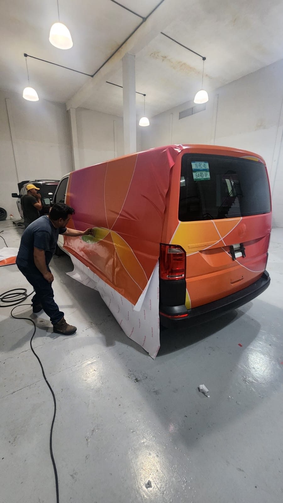 Instalador aplicando vinil de wrap sobre la carrocería de una camioneta