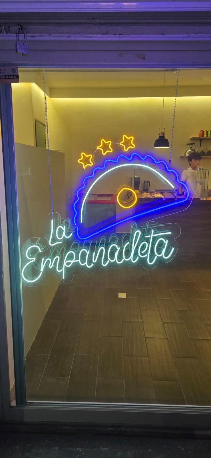Letrero de neón a color con forma de empanada en restaurante de Cancún