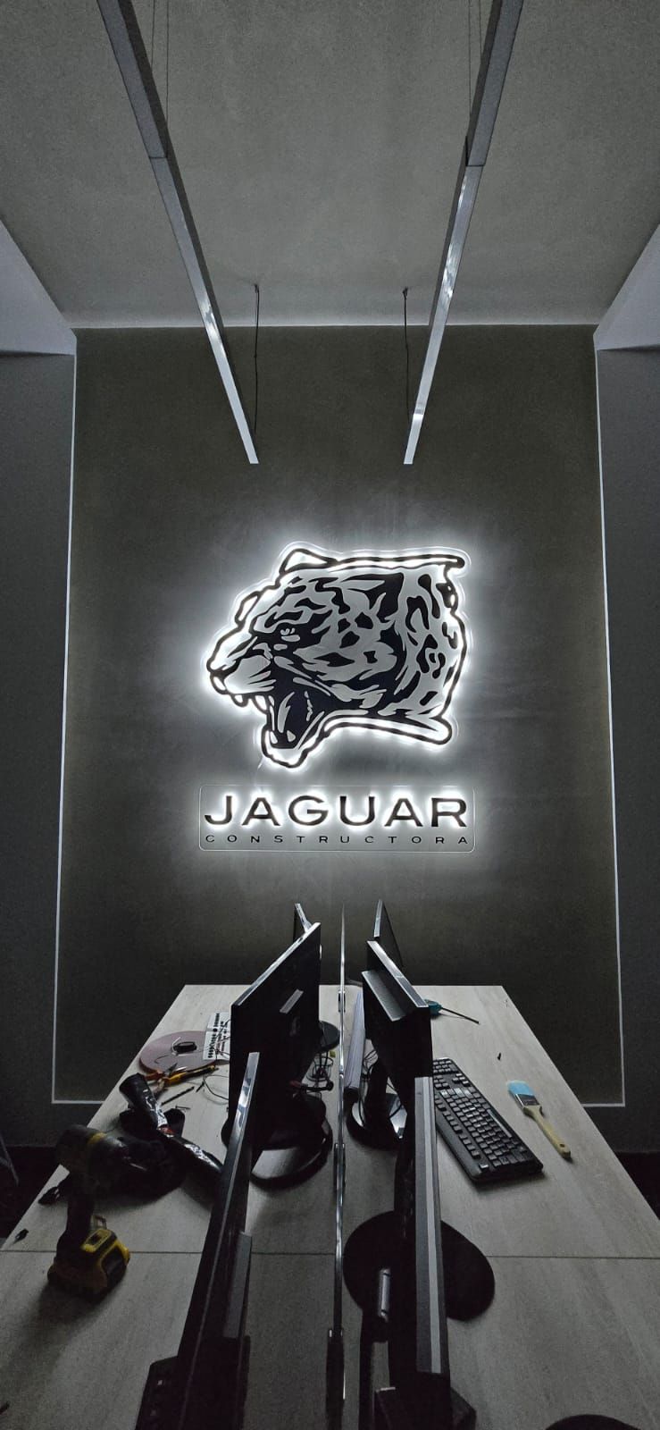 Logotipo de jaguar en neón blanco iluminado sobre muro oscuro